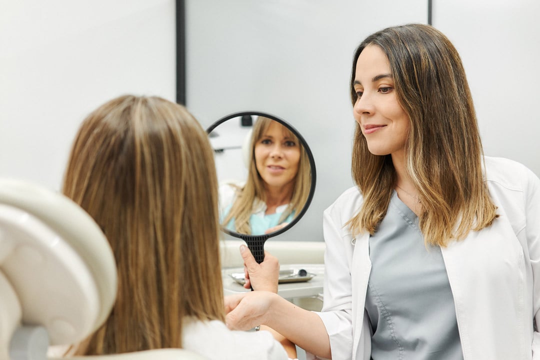 Paciente viendo su sonrisa después de tratamiento estético restaurador en Clínica Dental Augusto Leguía
