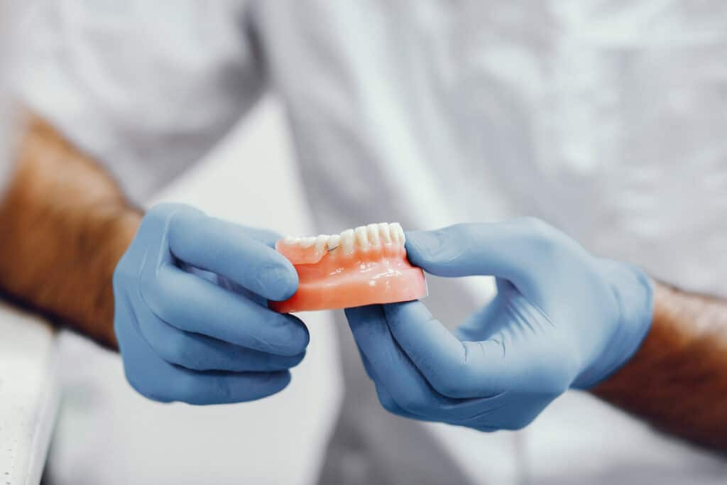Prótesis dental siendo sostenida por dentista en Clínica Dental Augusto Leguía