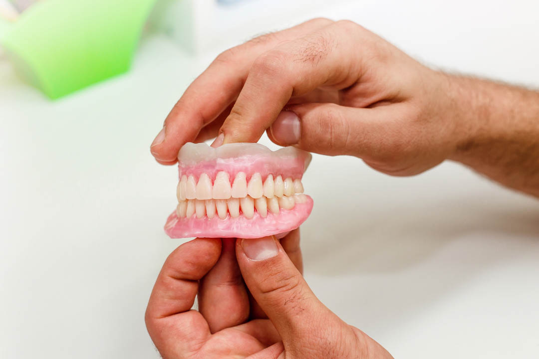 Prótesis dental completa sostenida por un dentista en la Clínica Dental Augusto Leguía