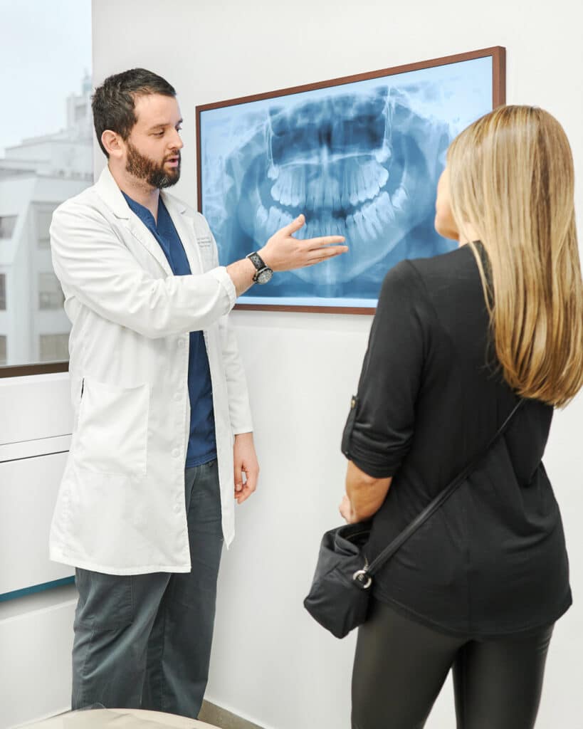 Dentista explicando tratamiento de TTM y bruxismo a paciente en Clínica Dental Augusto Leguía dentro de especialidades en odontología