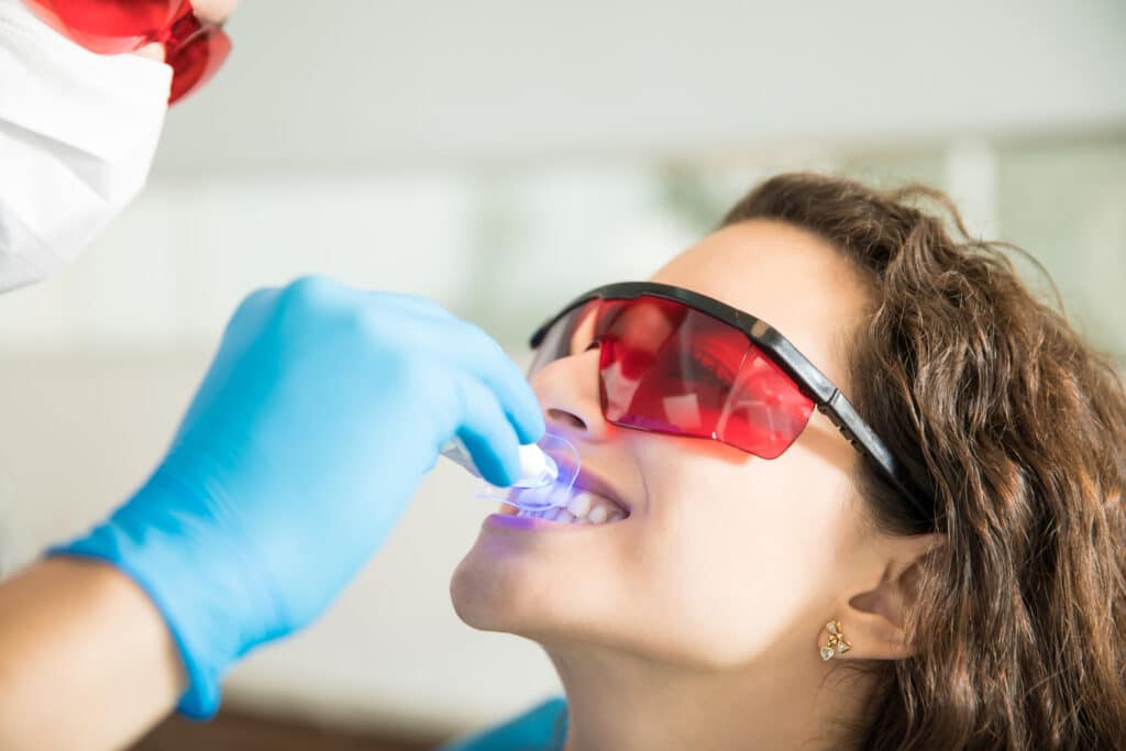 Mujer recibiendo un tratamiento de blanqueamiento dental profesional en sillón dental, con luz LED en la clínica Augusto Leguía